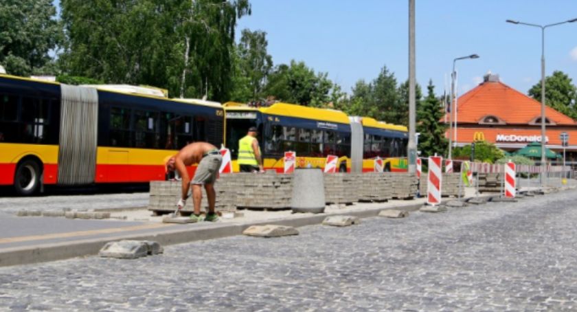 Robotnicy, pracujący w upalny dzień. W tle autobus i McDonald.